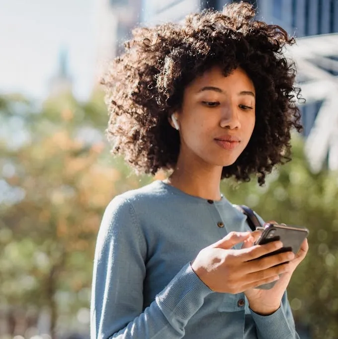 Woman in a Blue Long Sleeve Shirt Using Her Cell Phone